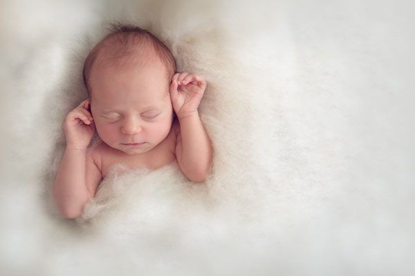 Wanneer newborn shoot inplannen. Babyfotografie slapende baby beide handjes omhoog. Babyfotografie