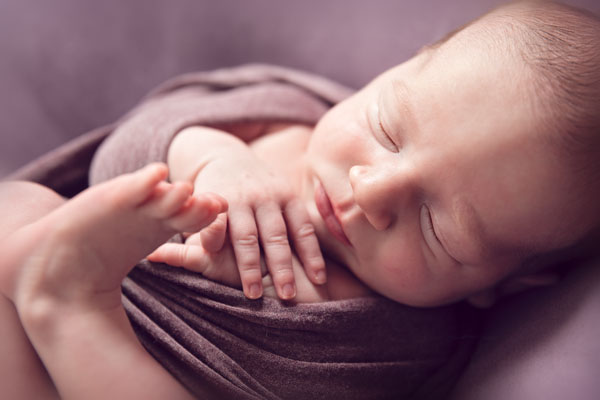 Babyfotografie slapende baby in paarse wrap.