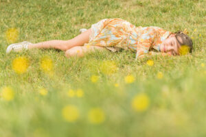 Meisje liggend op haar zij in het gras. Portret en familiefotografie