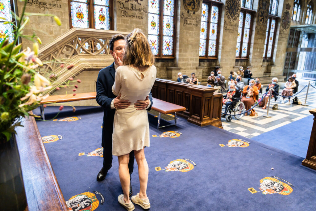 Koppel kussend in het gemeentehuis net na huwelijksceremonie. Huwelijksfotografie in reportagestijl.
